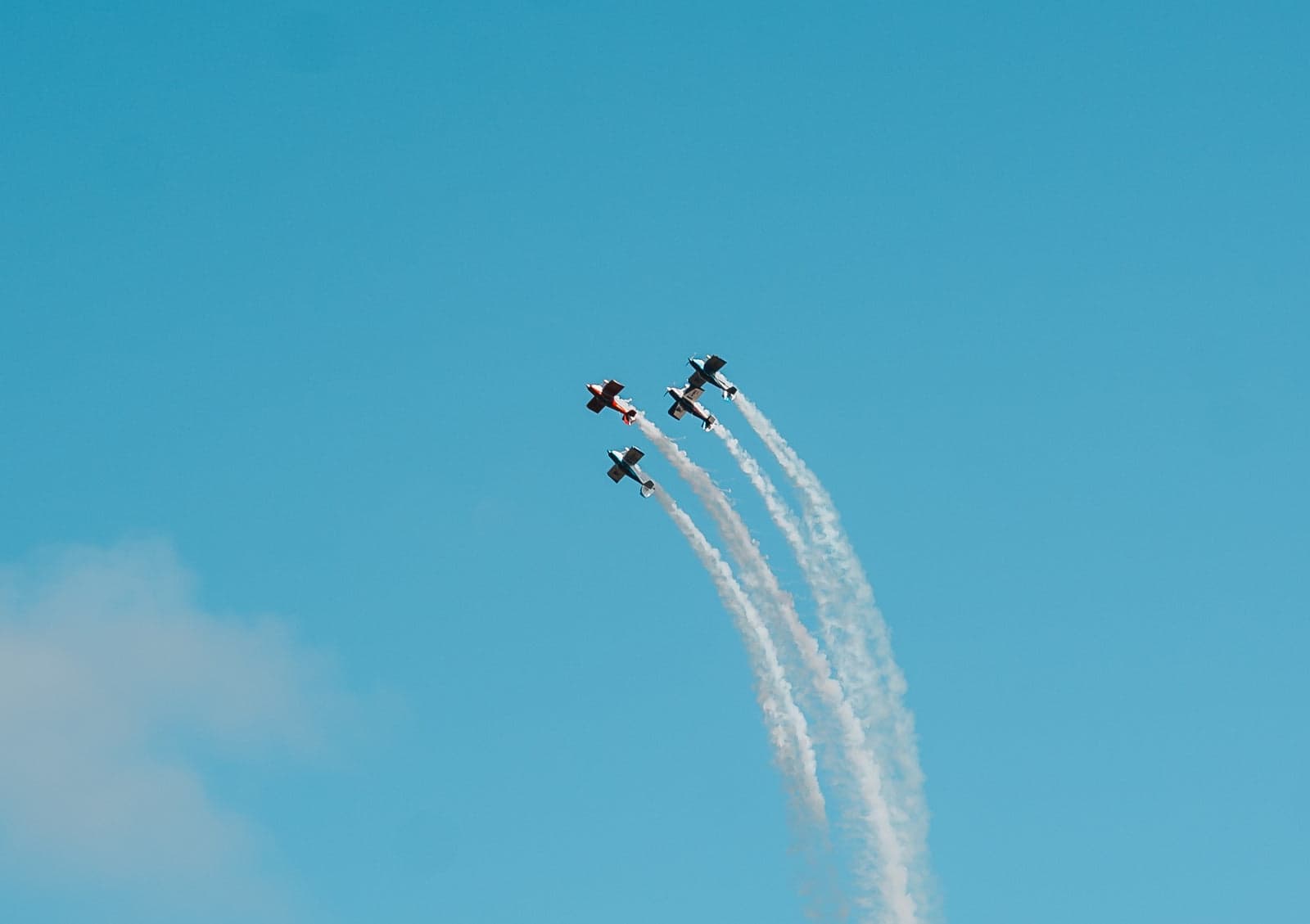 Four aerobatic aircraft trailing smoke in formation over the Aldinga Airshow