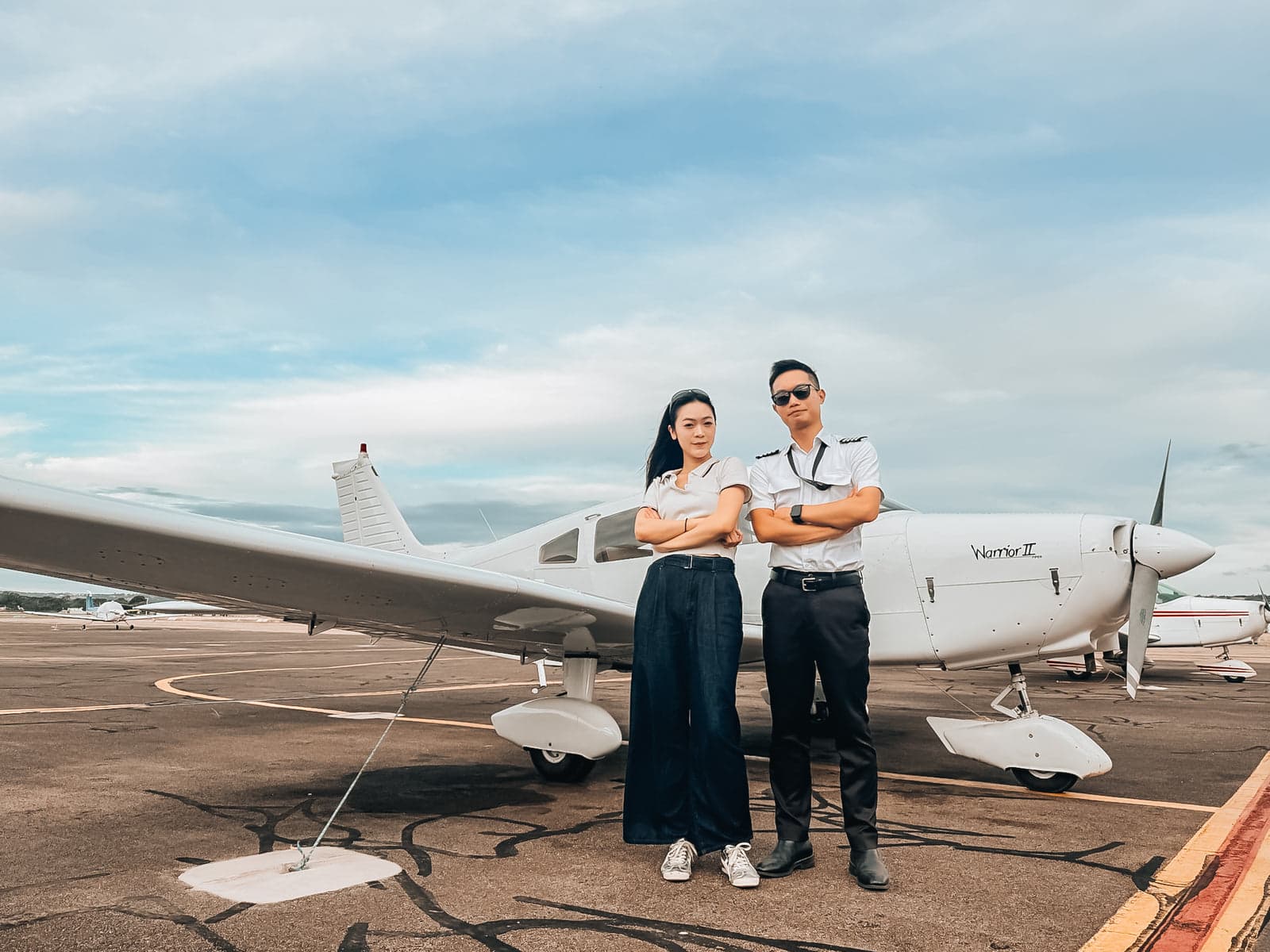 Two student pilots in uniform standing in front of a Piper Warrior II